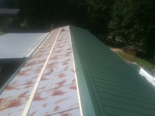 Old rusted panels beside newly installed green metal roofing — Wind Damage Roof Repair by Roofing Brothers in Hansen