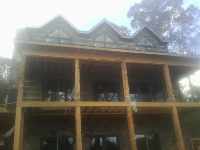 Dormers and porch framing on a large log home under construction — Roof Coating work by our crew in Hansen