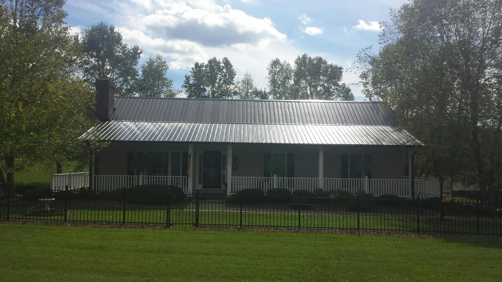 Gray metal roof on a brick ranch with a full width front porch — Gutter Guard Installation work by our crew in Hansen