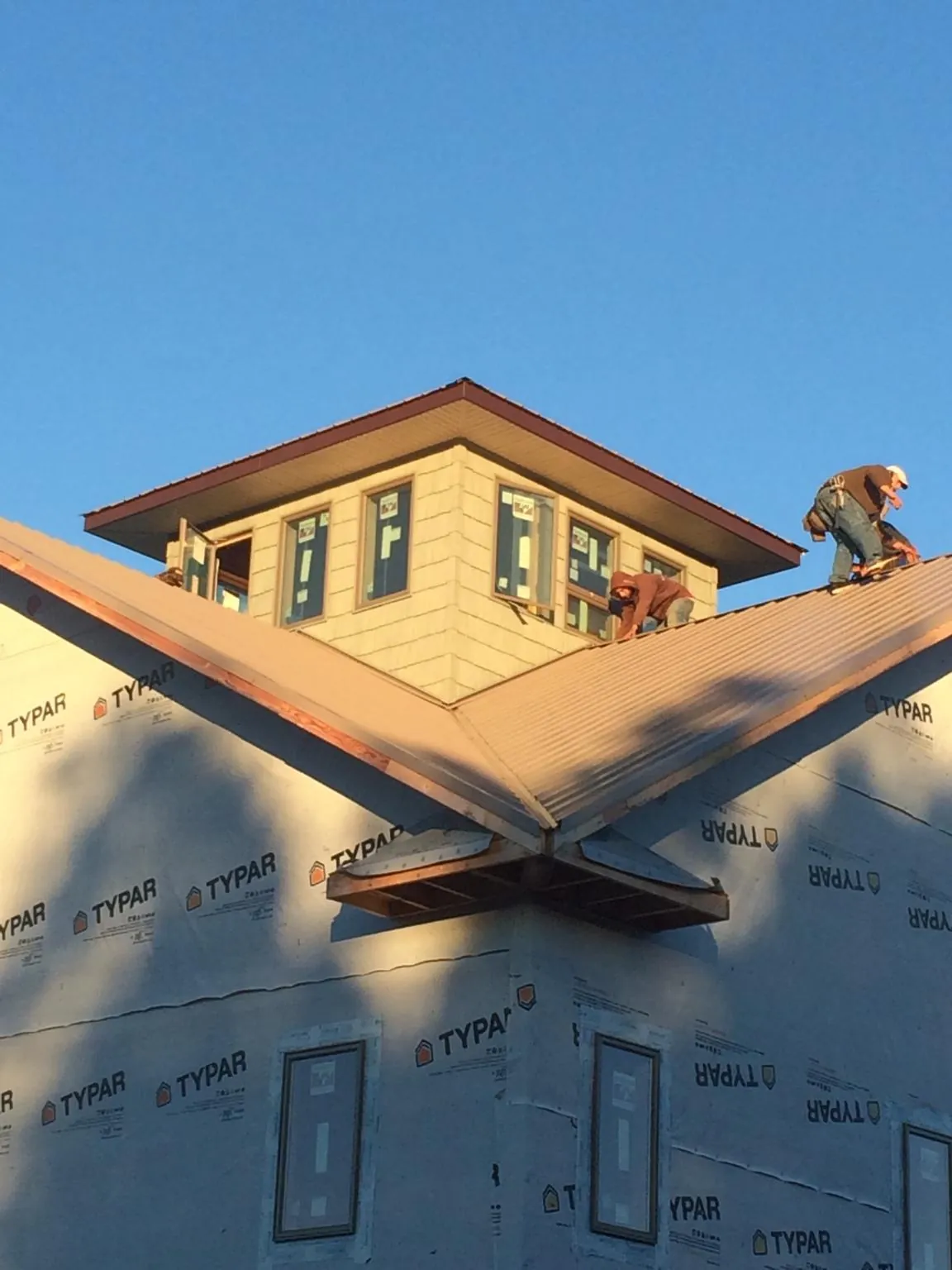 Roofers working around a rooftop cupola on a new metal roof at sunset — Roof Waterproofing in Hansen by Roofing Brothers
